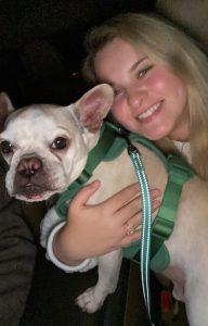 Emily smiling with her arm around her bulldog, Louis.