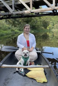 Emily sitting in a canoe with her bulldog, Louis.